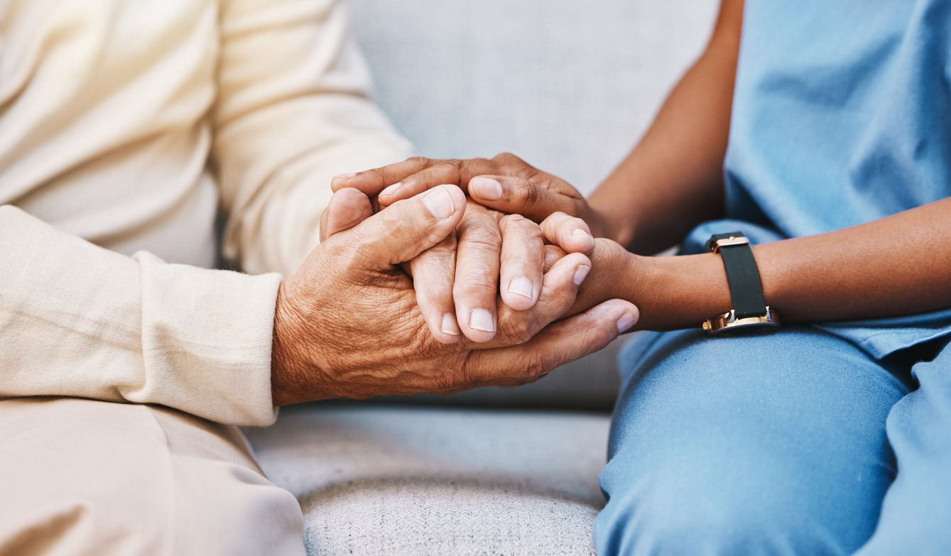 Nurse holding senior patient's hands