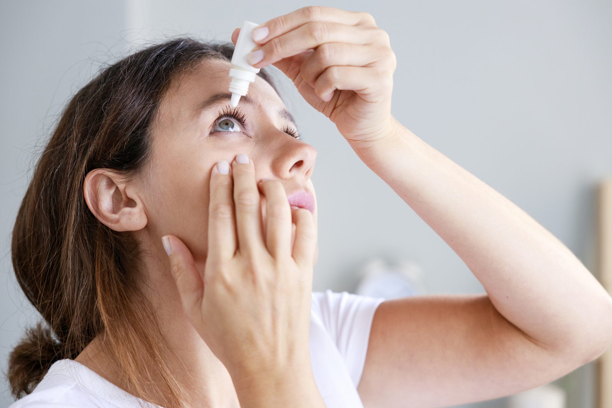 Woman using eye drops to relieve Sjögren's disease symptoms
