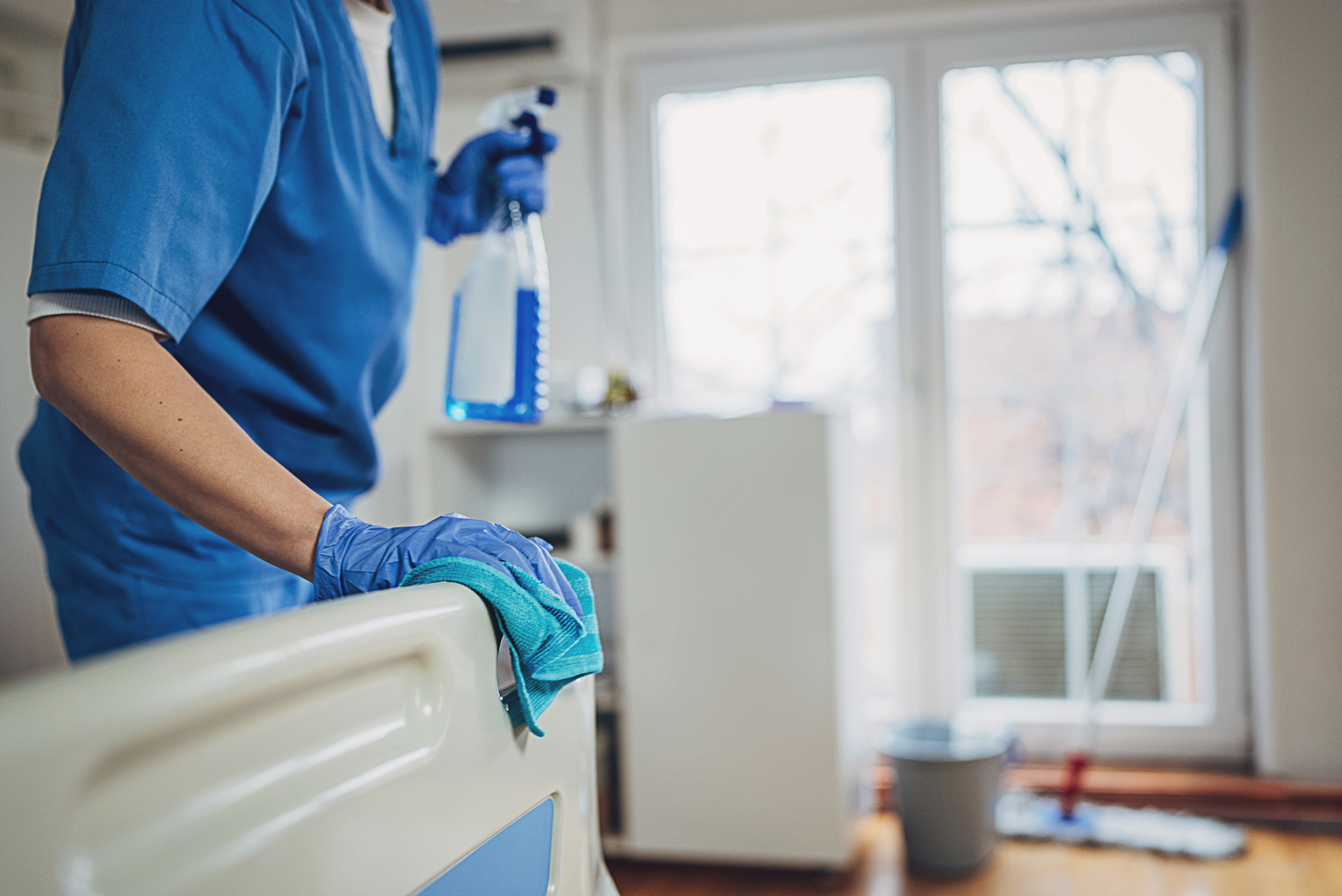 Nurse sanitizing hospital bed
