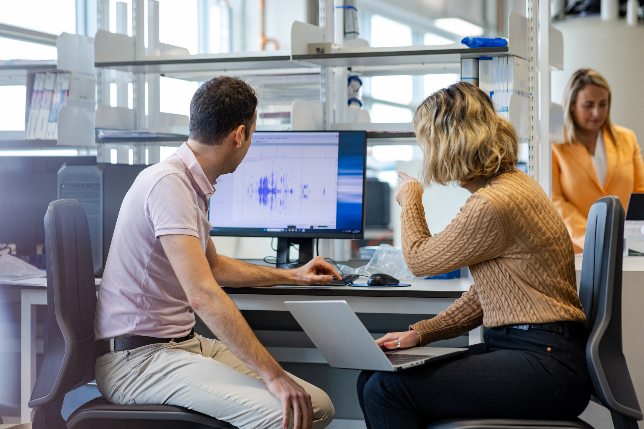 Researchers discussing in a lab, commenting data visualised on a computer screen