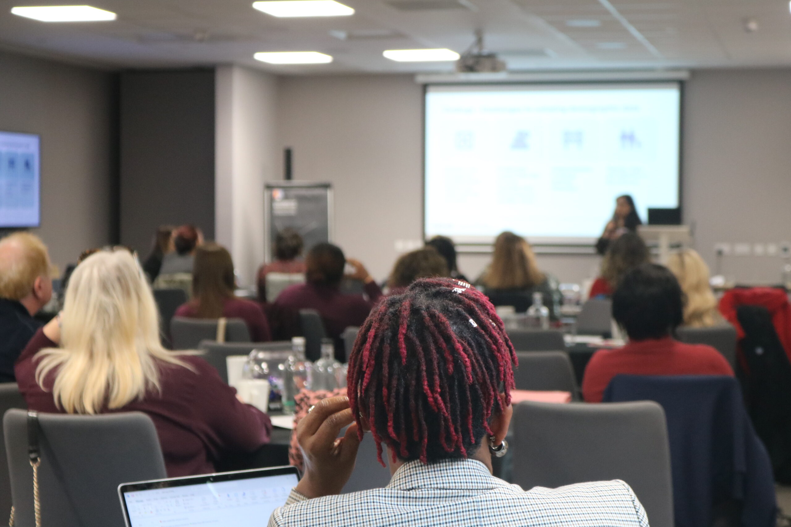 Full room of attendees viewed from the back