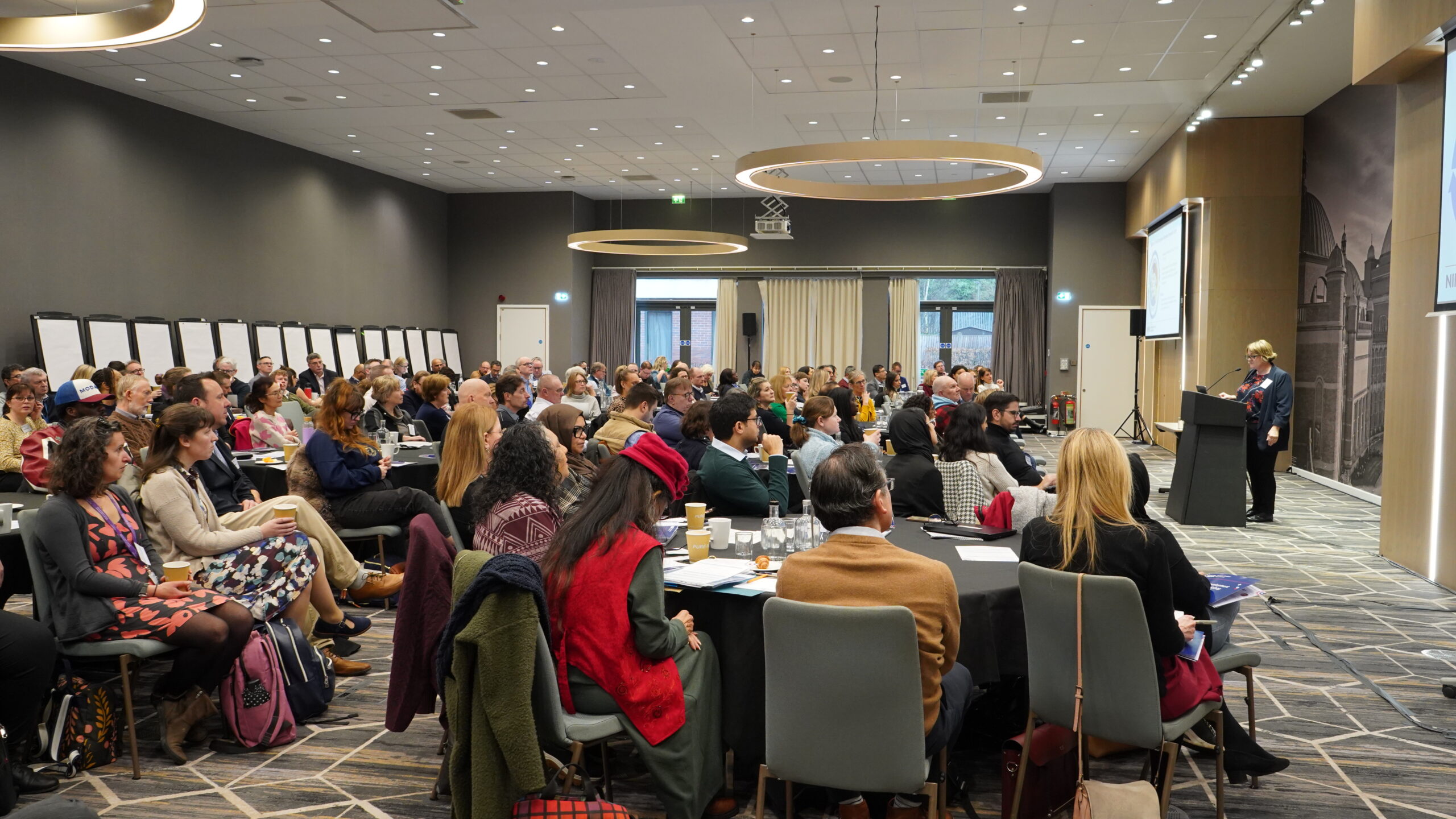 Full room of attendees with Vicki Day on stage