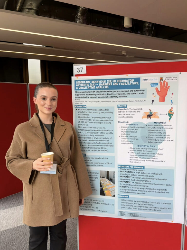 Florentia Kitas standing next to her poster at a conference