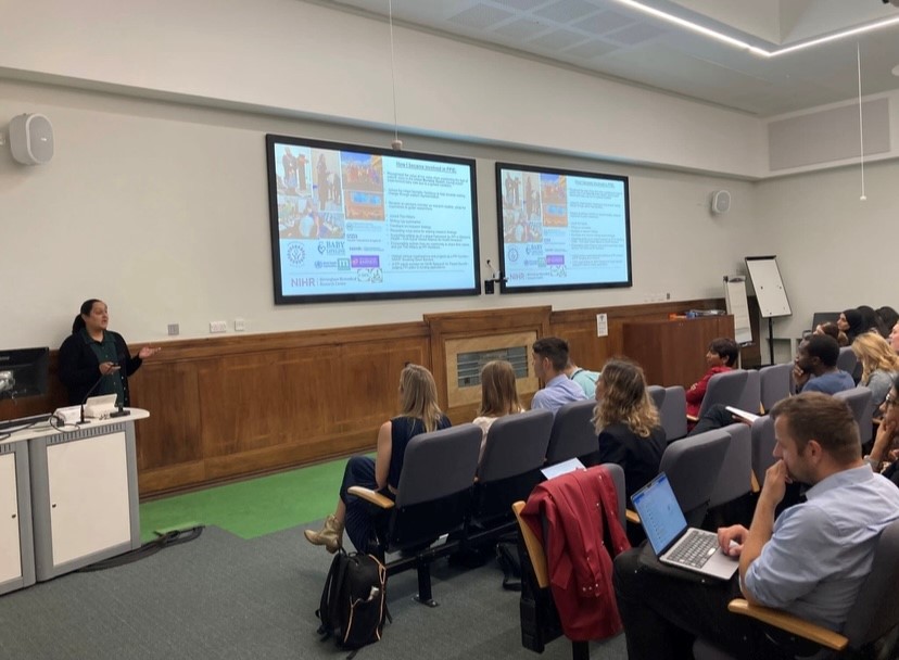 Woman presenting in front of a room of academics