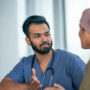 Male nurse speaks with patient wearing head covering
